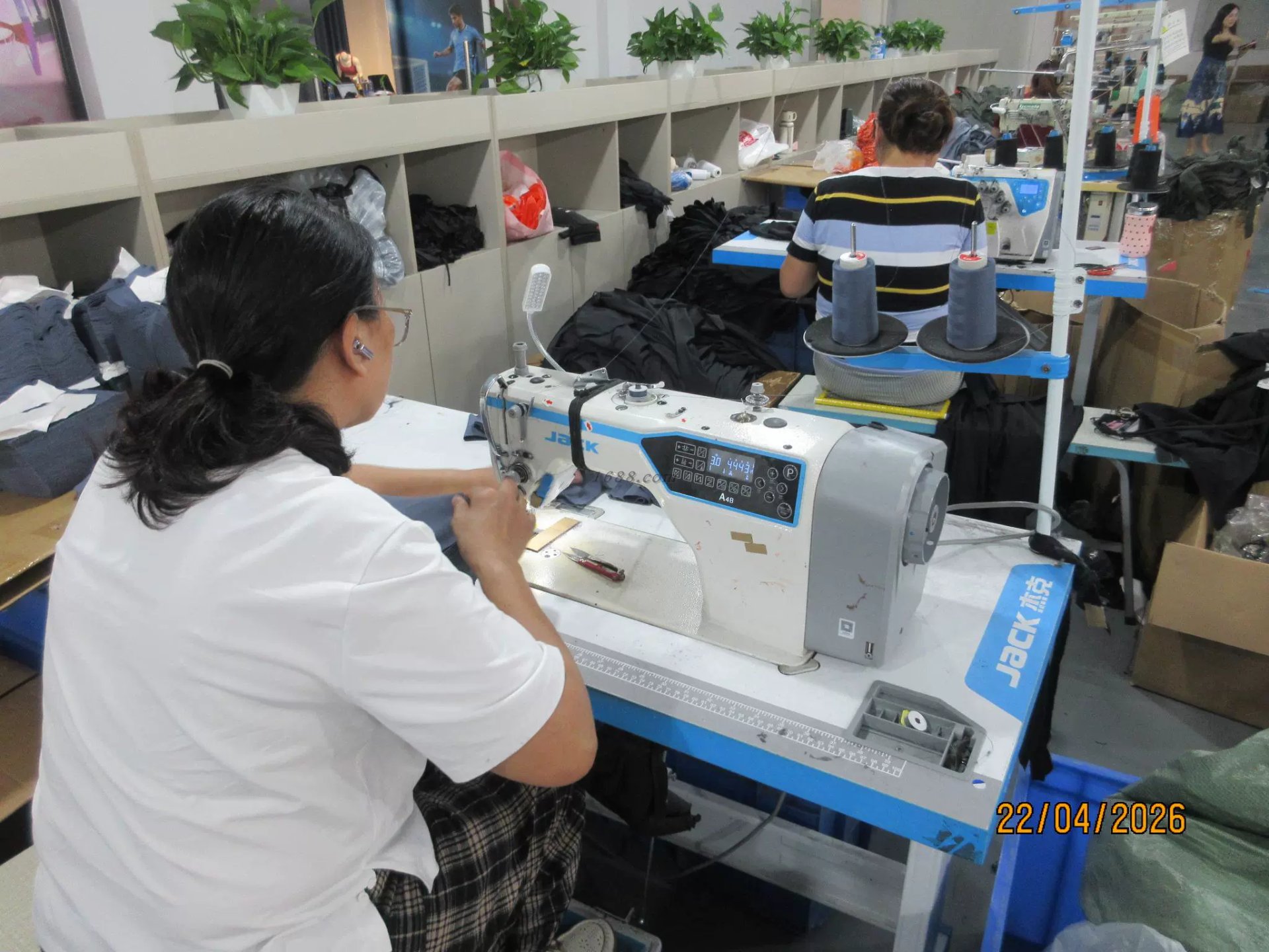 Worker at sewing machine producing ski protection equipment